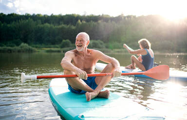 Aktives Seniorenpaar beim Paddeln auf einem See im Sommer. - HPIF15772