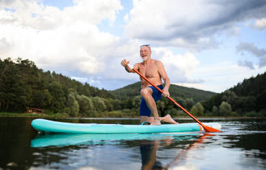 Vorderansicht eines älteren Mannes, der im Sommer auf einem See paddelt, Kopierraum. - HPIF15786