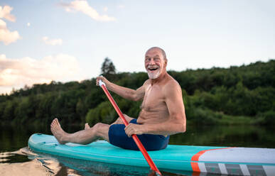 Vorderansicht eines älteren Mannes, der im Sommer auf einem See paddelt, Kopierraum. - HPIF15792