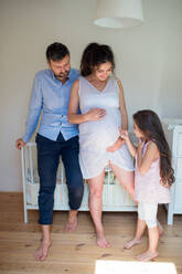 Porträt einer schwangeren Frau mit Ehemann und kleiner Tochter in einem Haus in der Vorderansicht. - HPIF15857