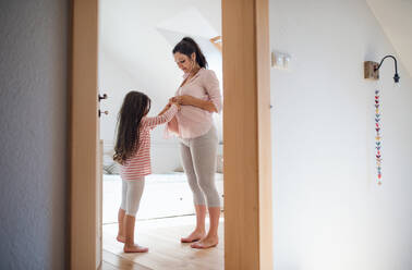 Seitenansicht Porträt der schwangeren Frau mit kleiner Tochter drinnen im Badezimmer zu Hause. - HPIF15872