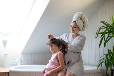 Seitenansicht Porträt der schwangeren Frau mit kleiner Tochter drinnen im Bad zu Hause, Bürsten der Haare. - HPIF15893