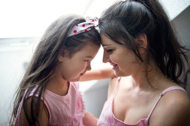 Portrait of mother and small daughter indoors at home, hugging. - HPIF15914