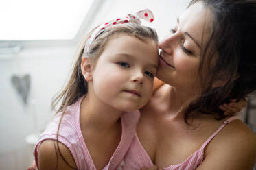Porträt einer Mutter und ihrer kleinen Tochter, die sich zu Hause umarmen. - HPIF15916