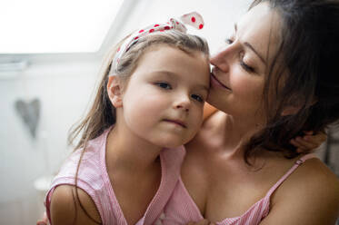 Portrait of mother and small daughter indoors at home, hugging. - HPIF15916