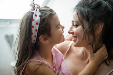 Portrait of mother and small daughter indoors at home, hugging. - HPIF15917