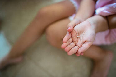 Mittelteil eines unkenntlichen kleinen Mädchens in einem Haus, das einen Milchzahn verliert. - HPIF15922
