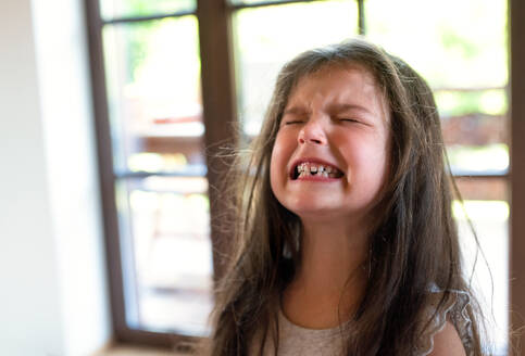 Porträt eines wütenden und schwierigen kleinen Mädchens in einem Haus, das weint. - HPIF15946