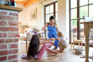 Happy pregnant woman with small children indoors at home, playing. - HPIF15957