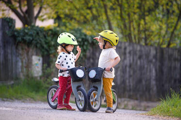 Glückliche kleine Kinder Junge und Mädchen mit Helmen und Balance Fahrräder im Freien spielen. - HPIF15970