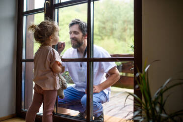 Der Arzt kommt, um die Familie in der Isolation zu sehen und zu begrüßen, das Fensterglas trennt sie. - HPIF15984