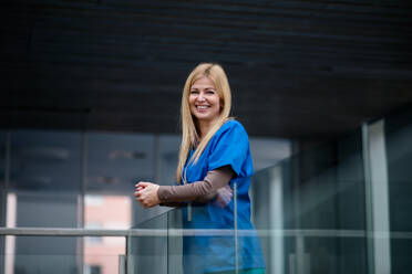 Portrait of doctor standing in hospital , leaning on glass railing. Copy space. - HPIF16040