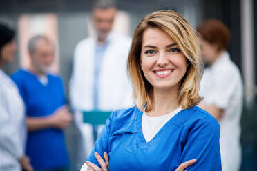 Porträt eines Arztes, der in einem Krankenhaus auf einer medizinischen Konferenz steht und in die Kamera schaut. - HPIF16049