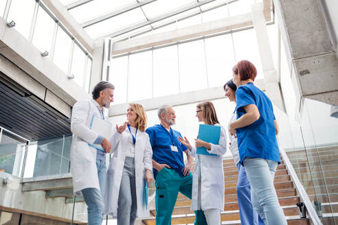 Eine Gruppe fröhlicher Ärzte steht auf einer Treppe und unterhält sich über medizinische Themen. - HPIF16060