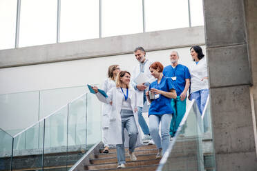 Eine Gruppe von Ärzten geht auf einer medizinischen Konferenz eine Treppe hinunter und unterhält sich. - HPIF16061