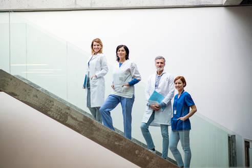 Eine Gruppe von Ärzten steht auf einer Treppe bei einer medizinischen Konferenz und unterhält sich. - HPIF16064