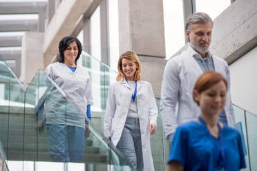 Eine Gruppe von Ärzten geht auf einer medizinischen Konferenz eine Treppe hinunter und unterhält sich. - HPIF16065