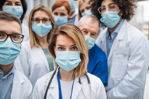 A group of doctors with face masks looking at camera, corona virus concept. - HPIF16081