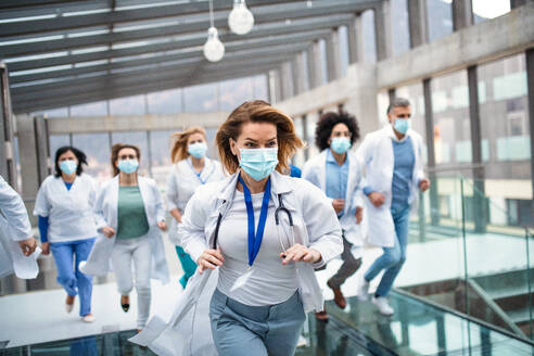 A front view of group of doctors with face masks running, corona virus concept. - HPIF16083