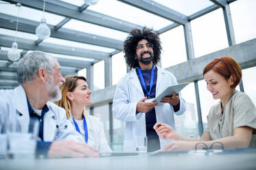 Eine Gruppe von Ärzten mit einem Tablet auf einer Konferenz, ein medizinisches Team, das Fragen diskutiert. - HPIF16094
