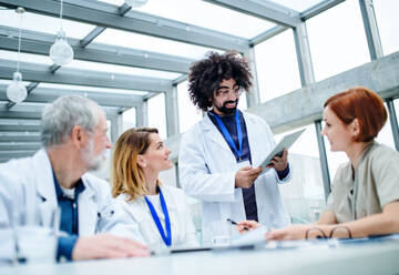 Eine Gruppe von Ärzten mit einem Tablet auf einer Konferenz, ein medizinisches Team, das Fragen diskutiert. - HPIF16095