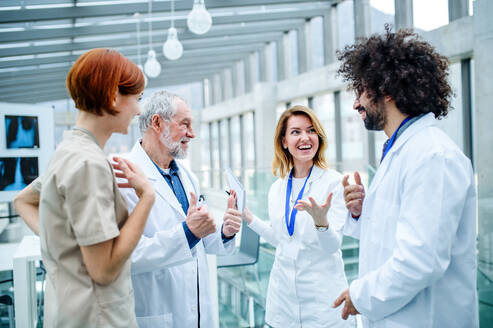 Eine Gruppe von Ärzten steht auf einer Konferenz, das Ärzteteam lacht bei der Besprechung von Problemen. - HPIF16106