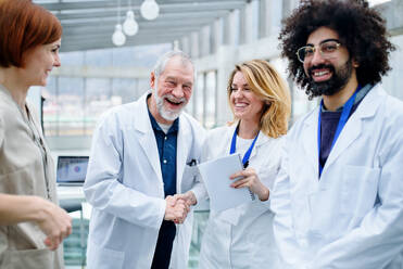 Group of doctors standing in corridor on medical conference, shaking hands. - HPIF16107