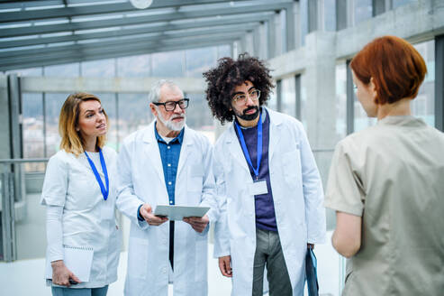 Eine Gruppe von Ärzten mit einem Tablet auf einer Konferenz, ein medizinisches Team, das sich unterhält und Probleme diskutiert. - HPIF16113