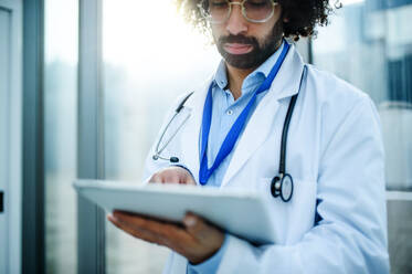 Porträt eines besorgten männlichen Arztes mit Tablet im Krankenhaus, Kopierraum. - HPIF16126