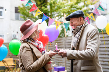 Ein glücklicher älterer Partner in einem Straßencafé in der Stadt, ein Paar feiert Geburtstag. Coronavirus-Konzept. - HPIF16210