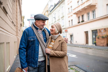 Porträt eines glücklichen älteren Paares, das auf einer Straße in der Stadt spazieren geht und Einkaufstüten trägt. - HPIF16217