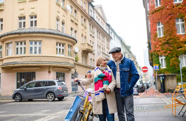 Porträt eines glücklichen älteren Paares mit Fahrrad im Freien auf einer Straße in der Stadt. - HPIF16233