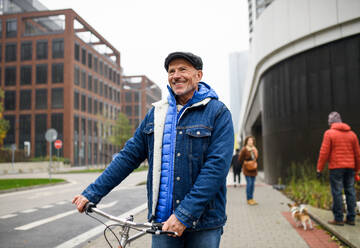 Glücklicher älterer Mann Pendler mit Fahrrad im Freien auf der Straße in der Stadt, zu Fuß. - HPIF16245