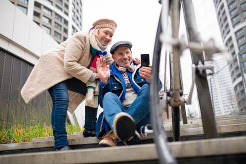 Ein lächelndes älteres Paar macht ein Selfie auf einem Bürgersteig in der Stadt und genießt den Moment - HPIF16248