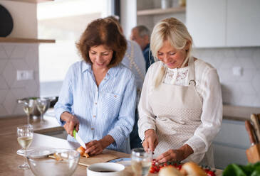 Frontansicht einer Gruppe fröhlicher älterer Freunde bei einer Dinnerparty zu Hause, beim Kochen. - HPIF16254