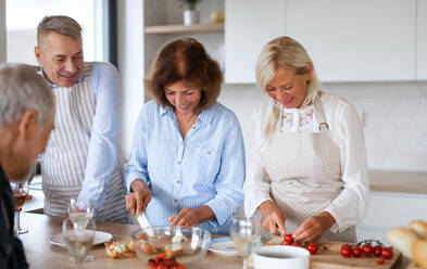 Frontansicht einer Gruppe fröhlicher älterer Freunde bei einer Dinnerparty zu Hause, beim Kochen. - HPIF16256