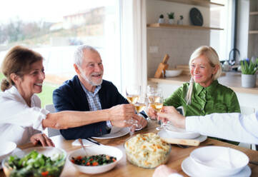 Group of senior friends enjoying dinner party at home, clinking glasses. - HPIF16270