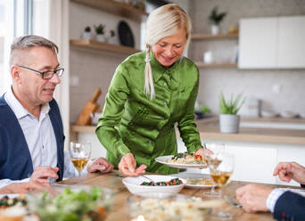 Eine Gruppe älterer Freunde genießt eine Dinnerparty zu Hause und isst. - HPIF16275
