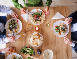 Draufsicht auf eine Gruppe älterer Freunde bei einer Dinnerparty zu Hause, die gerade essen, und einen Mittelteil. - HPIF16277