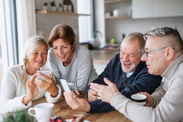 Eine Gruppe älterer Freunde zu Hause, die Smartphones benutzen. - HPIF16278