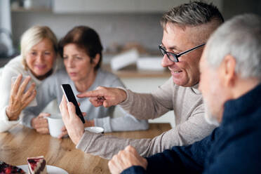 Eine Gruppe älterer Freunde zu Hause, die Smartphones benutzen. - HPIF16281