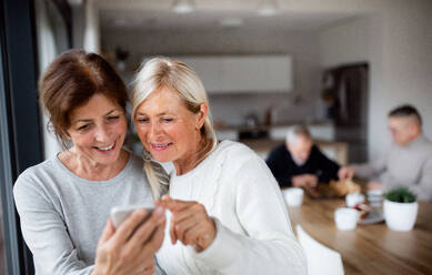 Eine Gruppe älterer Freunde zu Hause, die Smartphones benutzen. - HPIF16284