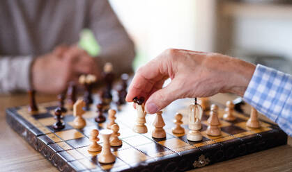 Mittelteil von unerkennbaren älteren Männern, die zu Hause Schach spielen. - HPIF16288