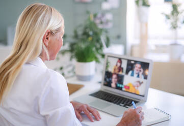 Ältere Geschäftsfrau mit Laptop sitzt drinnen im Home Office, Business Call Konzept. - HPIF16322