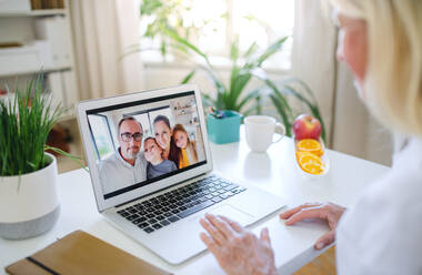 Happy senior woman with laptop indoors at home, family video call concept. - HPIF16327