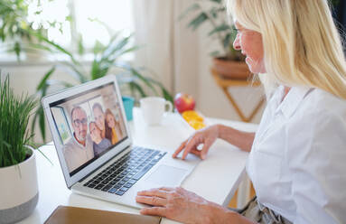 Happy senior woman with laptop indoors at home, family video call concept. - HPIF16328