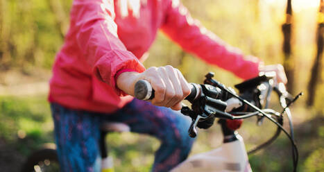 Unerkennbare aktive ältere Frau mit Fahrrad, die draußen in der Natur radelt. - HPIF16353