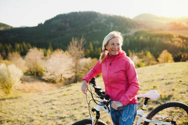 Aktive ältere Frau mit Fahrrad in der Natur, die sich ausruht. Kopierraum. - HPIF16356