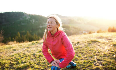 Smiling tourist woman wearing a backpack standing on a hill on a