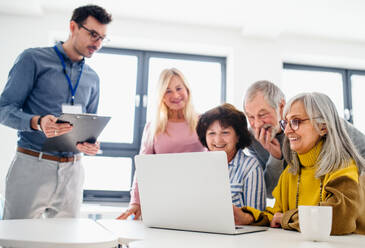 Eine Gruppe fröhlicher älterer Menschen, die einen Computer- und Technologiekurs besuchen. - HPIF16392
